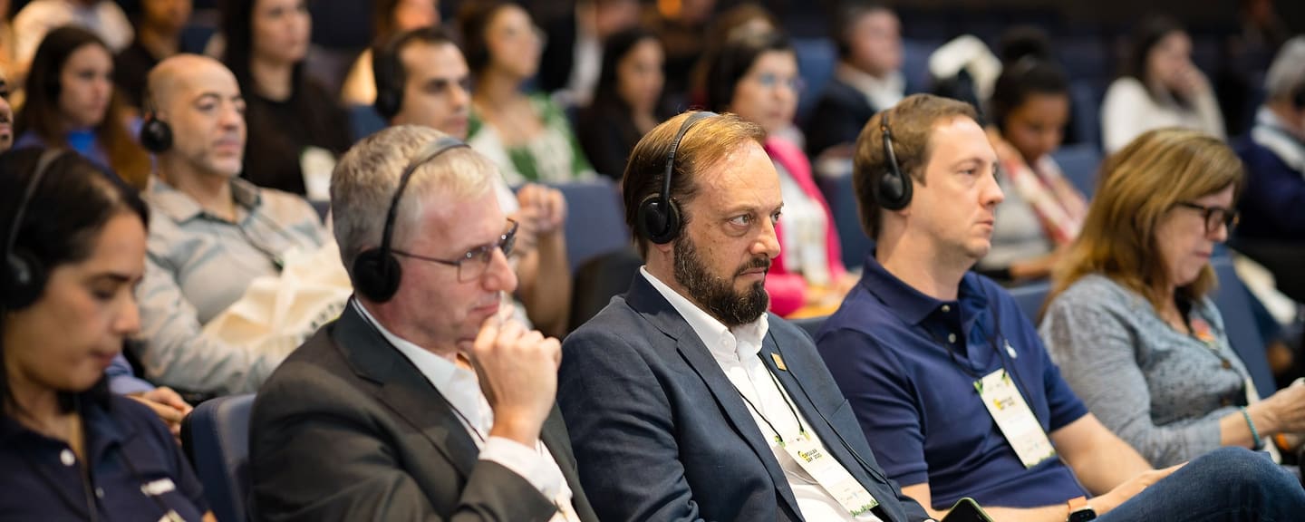 Plateia atenta durante o Circular Day 2025, com fones de tradução simultânea