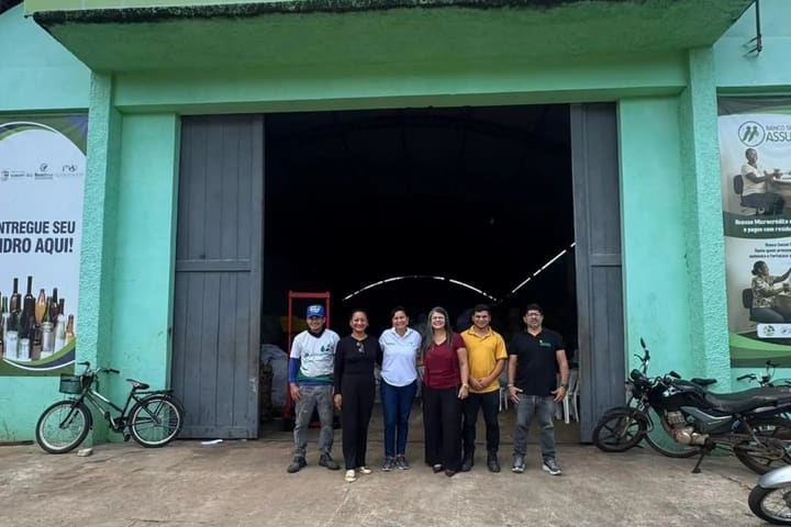 Cinco pessoas em frente ao galpão da coleta seletiva de Igarapé-Açu, com bicicletas ao lado da entrada.