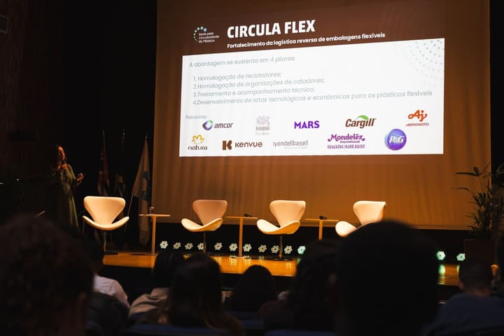 Apresentação da CirculaFlex no palco do II Fórum, com o programa de logística reversa de embalagens flexíveis no telão.