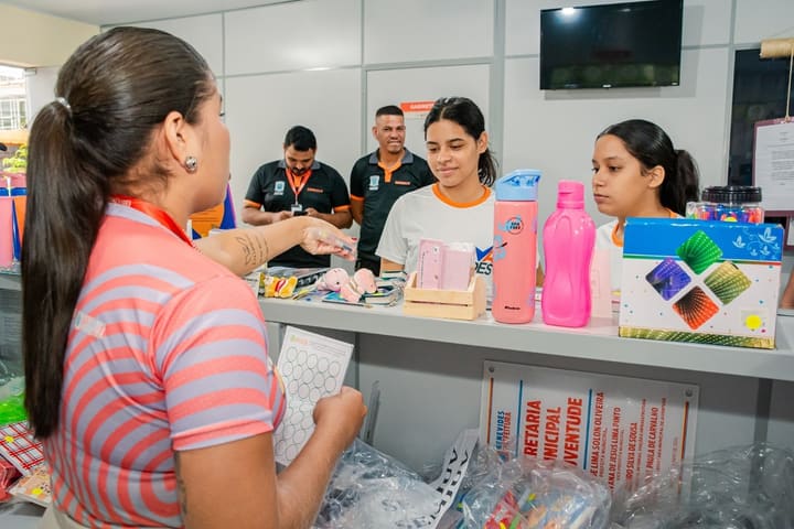 Balcão de troca do Recicla Cidade, com moradores escolhendo produtos pela moeda humanitária.