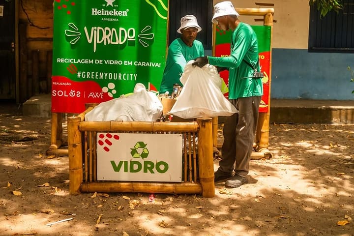 Dois catadores do Vidrado com sacos de vidro e o coletor de bambu, em Caraíva.