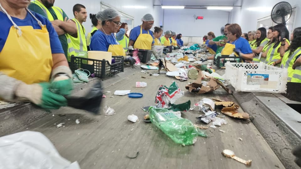 Trabalhadores e participantes de uma visita técnica na esteira de triagem da Coopercaps