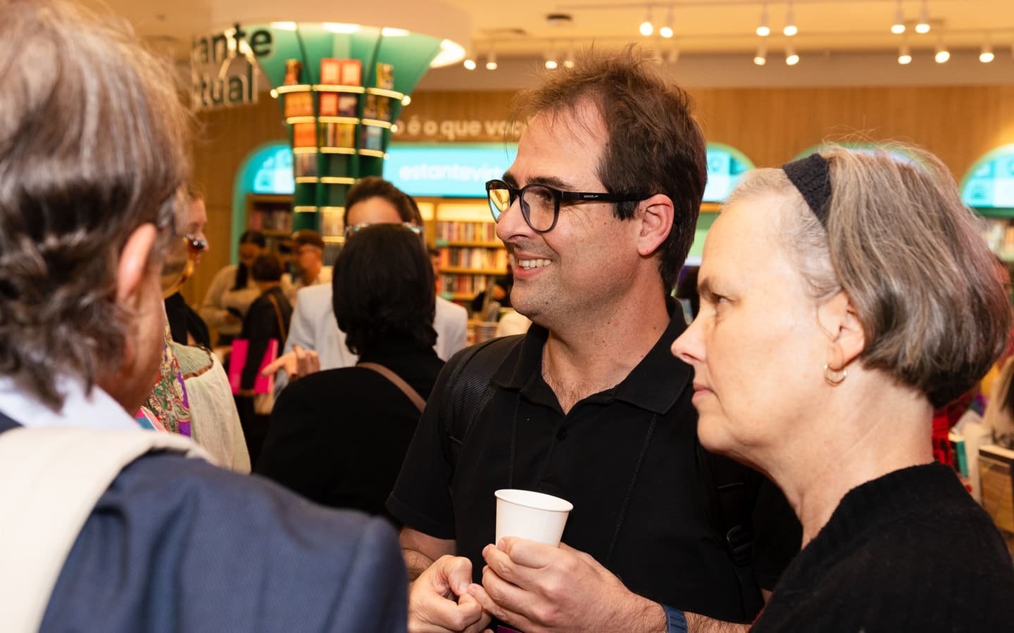 Participants wearing badges talk during a break at the II Fórum de Economia Circular.