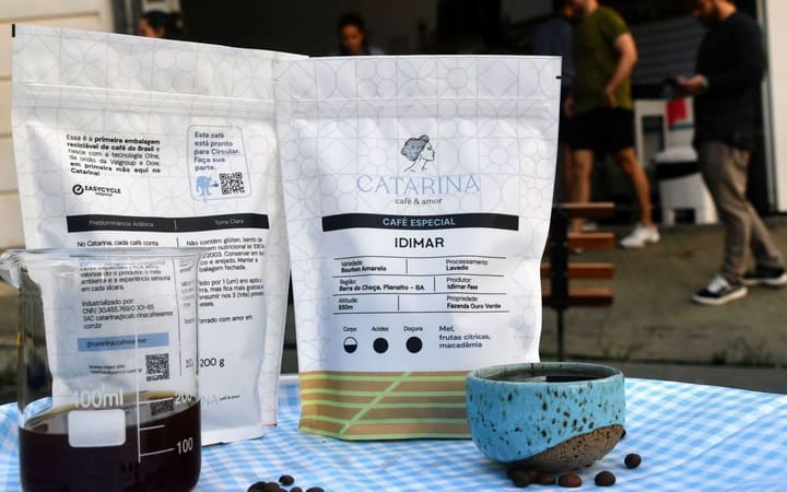 Front and back views of Catarina coffee packages beside a cup and coffee beans.
